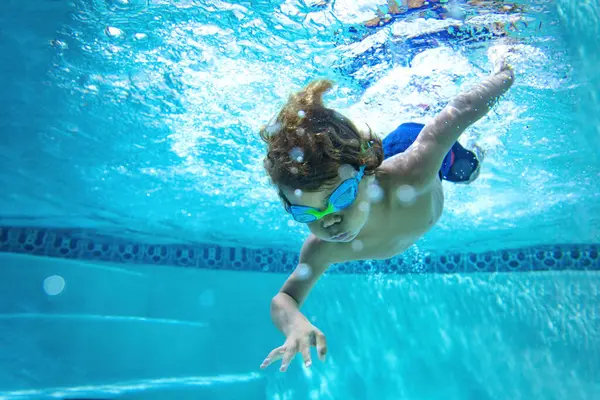 水下的小男孩在游泳池和护目镜的乐趣 暑假的乐趣 图库图片
