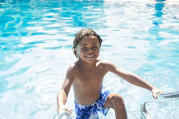 微笑着多样化的小男孩在游泳池里度假的乐趣 免版税图库照片