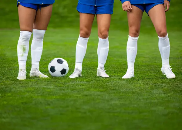 試合前に一緒に立っているサッカー選手の列 足と足だけを見せている アスレチックでフィットする女性サッカー選手は 任意の挑戦をプレーし 取る準備ができています ストック写真