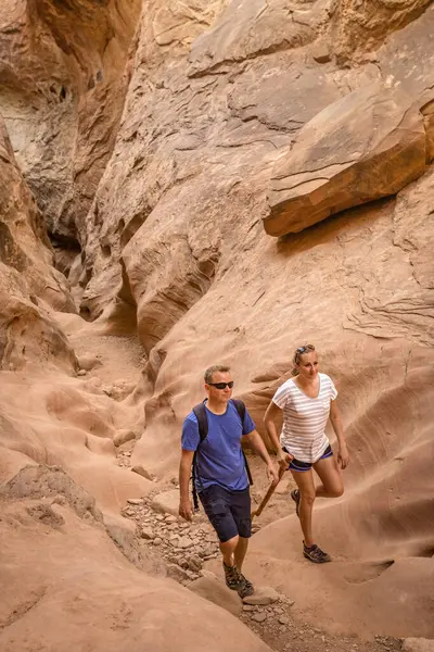 赤いロックスロットの峡谷をハイキングするカップル アメリカ合衆国南西部の驚くべき砂岩岩の形成を楽しむ ロイヤリティフリーのストック画像