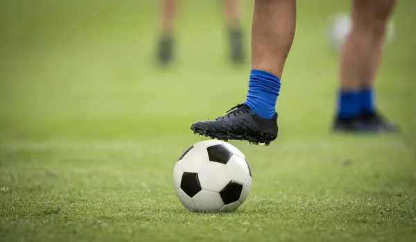 サッカー場でサッカーボールの上に休憩する足の近く グッドサッカーコンセプト写真 ロイヤリティフリーのストック写真