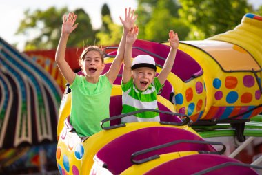 Oğlan ve Kız lunaparkta heyecan verici bir lunaparkta hız trenine biniyorlar. Kolları havada ve heyecandan bağırıyorlar. Yaz eğlence konsepti fotoğrafı