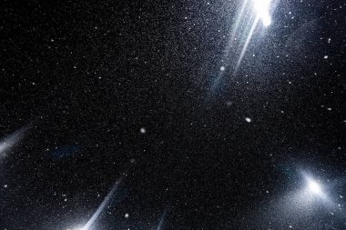Siyah arkaplanda uçan toz parçacıkları