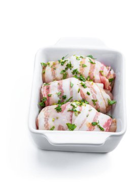 Raw Chicken  breasts wrapped in bacon in white dish isolated on white. Ready to cook 