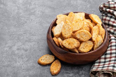 Gri arka planda ahşap kasede çıtır çıtır kızarmış ekmek. 