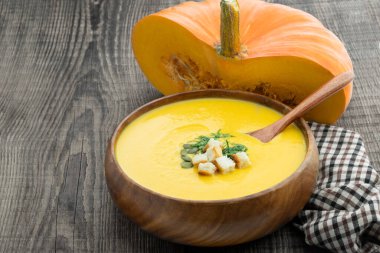Kabak kremalı çorba, ahşap kasede kırsal masada kızarmış ekmeklerle servis edilir. 