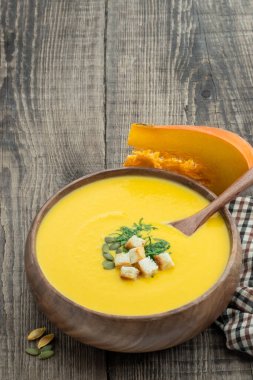Kabak kremalı çorba, ahşap kasede kırsal masada kızarmış ekmeklerle servis edilir. 