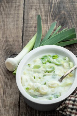 Tahta arka planda seramik kasede tereyağlı kremalı pırasa 