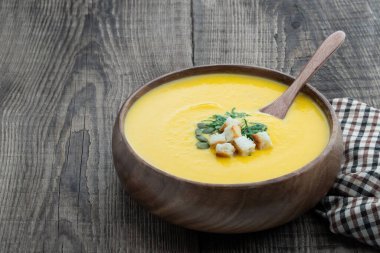 Kabak kremalı çorba, ahşap kasede kırsal masada kızarmış ekmeklerle servis edilir. 