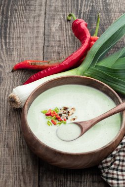 Kırsal masada, ahşap kasede acı biberli kremalı kabaklı pırasa çorbası. 