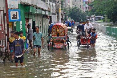 Rickshaw 'lar, 25 Ekim 2022' de Dhaka, Bangladeş 'te şiddetli kasırga etkisi yaratan şiddetli yağış nedeniyle Dhaka' nın sel basmış caddesinde yolcularla birlikte araba sürmeye çalıştı.