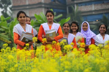 Bangladeş Köyü öğrencisi 1 Ocak 2015 'te Dhaka, Bangladeş' in Manikganj İlçesi 'nde ders kitaplarıyla toplanma alanında okula gidiyor.