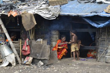 Bangladeş, Dhaka 'da demiryolunun yanındaki gecekondu mahallesindeki derme çatma evinin önünde yemek pişiren bir kadın. 13 Haziran 201
