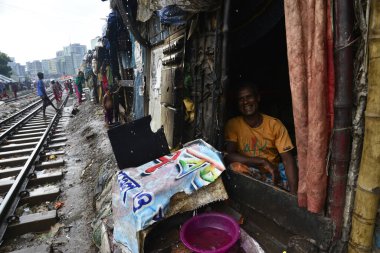 Bangladeş, Dhaka 'daki demiryolu hattının yanındaki derme çatma evde bir adam oturuyor. 13 Haziran 201