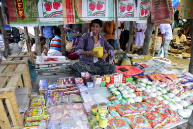 21 Haziran 2015 'te Bangladeş' in Narayanganj ilçesindeki Kaikkarateke haftalık pazarında müşterilerin ürün satmasını bekleyen bir dükkan sahibi