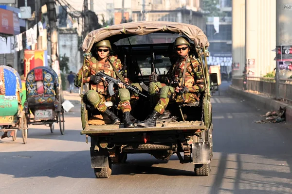 Bangladeş Ordusu personeli, 5 Ocak 2024 tarihinde Bangladeş 'in Dhaka kentinde yapılacak 12. Genel Seçimler için bir caddede devriye gezerken bir aracın arkasında oturuyor. Seçim güvenlik görevleri, barışçıl bir atmosfer ve durgunluğun sağlanmasına yardımcı olmaya başladı