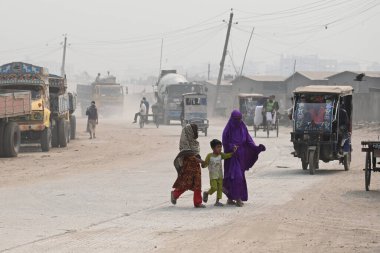 İnsanlar 30 Ocak 2024 'te Bangladeş' in Dhaka şehrinde tozlu bir yolda harekete geçtiler. Hava Kalite Endeksine göre, Dhaka City 'nin Havası' çok sağlıksız 'olarak sınıflandırıldı ve vatandaşlar için ciddi sağlık riskleri oluşturdu.