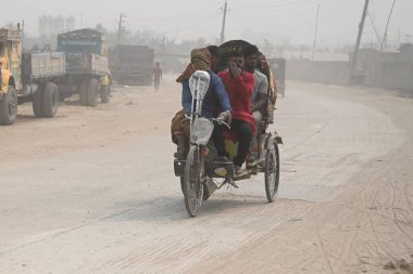 İnsanlar 30 Ocak 2024 'te Bangladeş' in Dhaka şehrinde tozlu bir yolda harekete geçtiler. Hava Kalite Endeksine göre, Dhaka City 'nin Havası' çok sağlıksız 'olarak sınıflandırıldı ve vatandaşlar için ciddi sağlık riskleri oluşturdu.