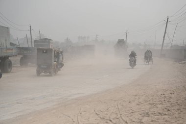 İnsanlar 30 Ocak 2024 'te Bangladeş' in Dhaka şehrinde tozlu bir yolda harekete geçtiler. Hava Kalite Endeksine göre, Dhaka City 'nin Havası' çok sağlıksız 'olarak sınıflandırıldı ve vatandaşlar için ciddi sağlık riskleri oluşturdu.