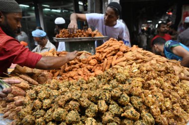 Sokak satıcısı, 12 Mart 2024 'te Bangladeş' in Dhaka kentindeki geleneksel iftar pazarında kutsal Ramazan ayı gündüz orucunu kırmak için iftar yiyeceği satıyor.