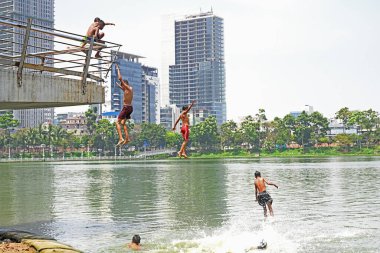 Çocuklar 3 Nisan 2024 'te Bangladeş, Dhaka' da sıcak bir yaz günü bir gölde banyo yaparlar.