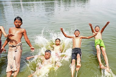 Çocuklar 3 Nisan 2024 'te Bangladeş, Dhaka' da sıcak bir yaz günü bir gölde banyo yaparlar.
