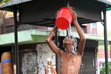 27 Nisan 2024 'te Dhaka, Bangladeş' te sıcak hava dalgası sırasında yol kenarındaki bir su boru hattından banyo yapan bir çocuk.