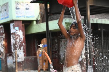 27 Nisan 2024 'te Dhaka, Bangladeş' te sıcak hava dalgası sırasında yol kenarındaki bir su boru hattından banyo yapan bir çocuk.