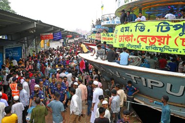 Yolcular, 14 Haziran 2024 'te Bangladeş' in Dhaka kentindeki Sadarghat Fırlatma Terminali 'nde düzenlenen Kurban Bayramı bayramını kutlamak üzere başkenti Dhaka' daki köylerine dönmek üzere feribot terminalinde toplanıyorlar.. 