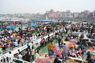 Yolcular, 14 Haziran 2024 'te Bangladeş' in Dhaka kentindeki Sadarghat Fırlatma Terminali 'nde düzenlenen Kurban Bayramı bayramını kutlamak üzere başkenti Dhaka' daki köylerine dönmek üzere feribot terminalinde toplanıyorlar.. 