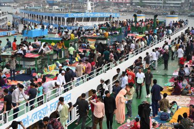 Yolcular, 14 Haziran 2024 'te Bangladeş' in Dhaka kentindeki Sadarghat Fırlatma Terminali 'nde düzenlenen Kurban Bayramı bayramını kutlamak üzere başkenti Dhaka' daki köylerine dönmek üzere feribot terminalinde toplanıyorlar.. 