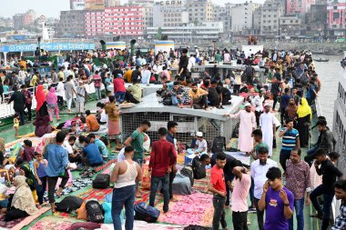 Yolcular, 14 Haziran 2024 'te Bangladeş' in Dhaka kentindeki Sadarghat Fırlatma Terminali 'nde düzenlenen Kurban Bayramı bayramını kutlamak üzere başkenti Dhaka' daki köylerine dönmek üzere feribot terminalinde toplanıyorlar.. 