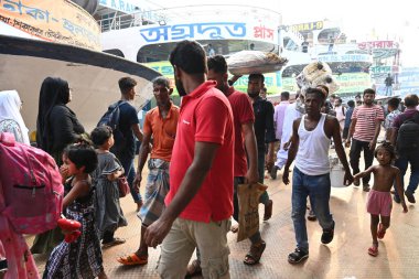 Yolcular, 14 Haziran 2024 'te Bangladeş' in Dhaka kentindeki Sadarghat Fırlatma Terminali 'nde düzenlenen Kurban Bayramı bayramını kutlamak üzere başkenti Dhaka' daki köylerine dönmek üzere feribot terminalinde toplanıyorlar.. 