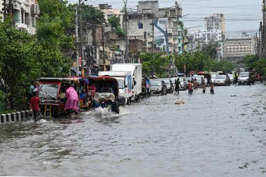 26 Haziran 2024 'te Bangladeş, Dhaka' da şiddetli muson yağmurlarının yol açtığı sular altında kalmış sokaklarda araçlar ve çekçekçekçekçekler yolcuları götürmeye çalışıyor.. 