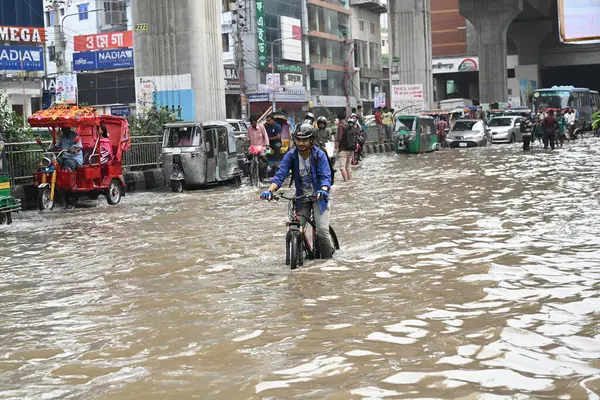 3 Eylül 2024 'te sağanak yağış neredeyse durgunluğa yol açtıktan sonra araçlar ve Rickshaw' lar Dhaka 'nın sulak sokaklarında yolcularla birlikte araba sürmeye çalışırlar.. 