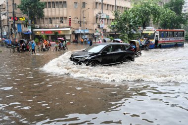 5 Ekim 2024 'te Bangladeş' te sağanak yağış neredeyse durgunluğa yol açtıktan sonra, araçlar ve Rickshawlar Dhaka şehrinin sulak sokaklarında yolcularla birlikte sürmeye çalışırlar.. 