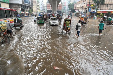 5 Ekim 2024 'te Bangladeş' te sağanak yağış neredeyse durgunluğa yol açtıktan sonra, araçlar ve Rickshawlar Dhaka şehrinin sulak sokaklarında yolcularla birlikte sürmeye çalışırlar.. 