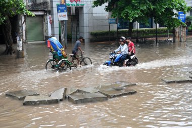 5 Ekim 2024 'te Bangladeş' te sağanak yağış neredeyse durgunluğa yol açtıktan sonra, araçlar ve Rickshawlar Dhaka şehrinin sulak sokaklarında yolcularla birlikte sürmeye çalışırlar.. 