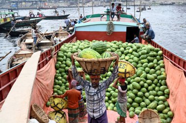İşçiler 21 Mart 2025 'te Dhaka, Bangladeş' teki Buriganga Nehri 'nin kıyısındaki bir tekneden karpuz indirirler. Ülkenin dört bir yanından yüzlerce meyve tüccarı yaz mevsiminde meyvelerini toptan satmak için başkente geldi.