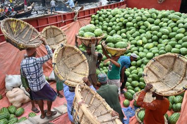 İşçiler 21 Mart 2025 'te Dhaka, Bangladeş' teki Buriganga Nehri 'nin kıyısındaki bir tekneden karpuz indirirler. Ülkenin dört bir yanından yüzlerce meyve tüccarı yaz mevsiminde meyvelerini toptan satmak için başkente geldi.