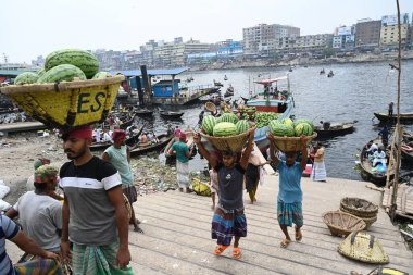 İşçiler 21 Mart 2025 'te Dhaka, Bangladeş' teki Buriganga Nehri 'nin kıyısındaki bir tekneden karpuz indirirler. Ülkenin dört bir yanından yüzlerce meyve tüccarı yaz mevsiminde meyvelerini toptan satmak için başkente geldi.
