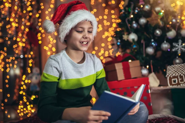 Happy Boy Lying Front Floor Christmas Tree Reading Book Surrounded — Zdjęcie stockowe