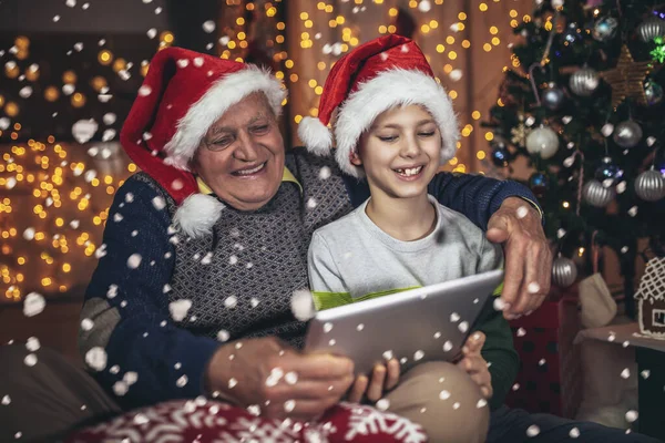 Grootvader Kleinzoon Zitten Stoel Kijken Naar Digitale Tablet Tijdens Kerst — Stockfoto