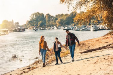 Ebeveynler ve oğulları nehir kenarında yürüyor kırsalda tatil yapıyorlar.