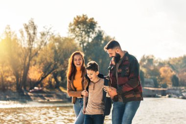 Ebeveynler ve oğulları nehir kenarında yürüyor kırsalda tatil yapıyorlar.