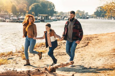 Ebeveynler ve oğulları nehir kenarında yürüyor kırsalda tatil yapıyorlar.