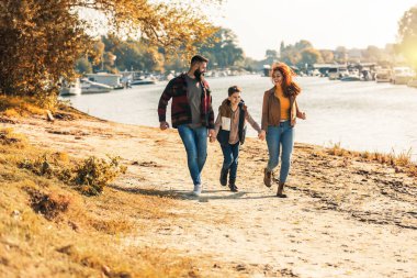 Ebeveynler ve oğulları nehir kenarında yürüyor kırsalda tatil yapıyorlar.