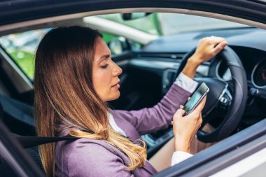 Genç bayan sürücü telefonuna bakıyor.
