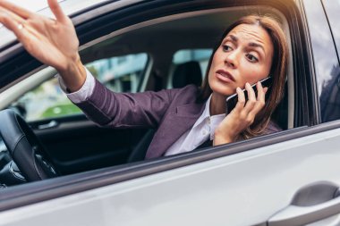 Angry young woman using phone pissed off by drivers in front of her and gesturing with hands