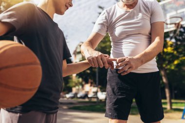 Babası basketbol oynadıktan sonra parmak travması geçiren çocuğa yardım ediyor. Spor Sakatlığı. 